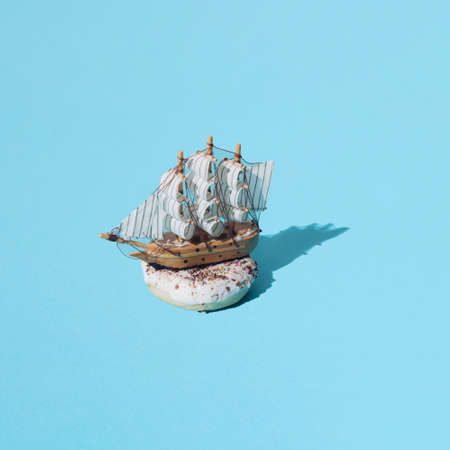 Small wooden home decoration pirate ship with white sails on donut with white glaze and colorful...
