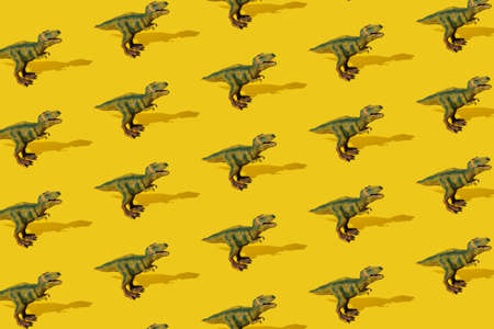 Dinosaurs Tyrannosaurus rex on a yellow background. Pattern. T-rex toy.の写真素材