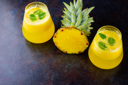 Pineapple cocktail on a dark background. Cold pineapple cocktail with mint. Summer tropical cocktail on a black background. Healthy drink. Top view. Copy spaceの写真素材