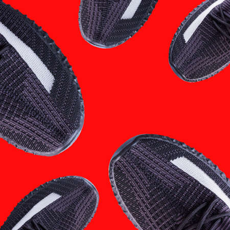 Creative collage with black running shoes. Collage pattern, black sneakers on red background. Fashion blog, sport lifestyle. Flat lay. Top viewの写真素材
