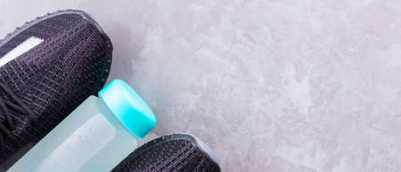 Fitness concept with sneakers and bottle of water. Sports equipment on a gray background. Healthy...