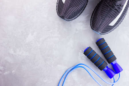 Fitness concept with black sneakers and jump rope. Sports equipment on a gray background. Healthy lifestyle concept. Top viewの写真素材
