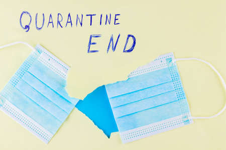 Quarantine end. Two parts of cut surgical mask on a yellow background. Covid-19 Completion Concept....