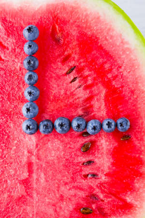 Watermelon and blueberries on white background. Half of watermelon on wooden boards. Berries for vegan. Clock hands of berries. Watch from foodの写真素材