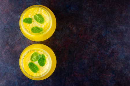 Pineapple juice on a dark background. Juice for detox in the glass. Pineapple smoothie with fresh pineapple. Summer drink on a black background. Top view. Copy spaceの写真素材
