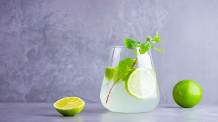 Mojito cocktail with lime and mint in glass. Two glasses of mojito on a gray background. Refreshing mint cocktail with lime. Infused waterの写真素材