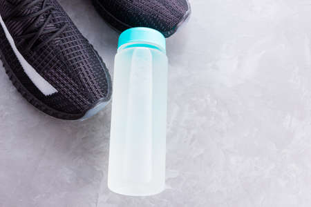 Fitness concept with sneakers and bottle of water. Sports equipment on a gray background. Healthy lifestyle concept. Copy space. Top viewの写真素材