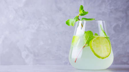 Mojito cocktail with lime and mint in glass. Mojito in glass on a gray background. Refreshing mint cocktail with lime. Infused water. Copy spaceの写真素材
