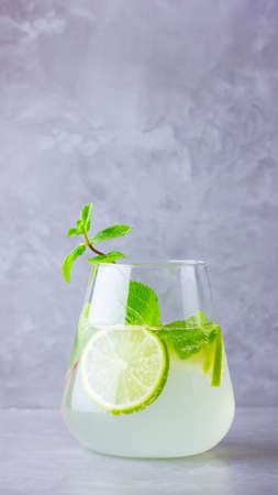 Mojito cocktail with lime and mint in glass. Mojito in glass on a gray background. Refreshing mint...