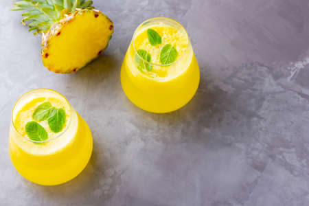 Pineapple cocktail on a gray background. Cold pineapple cocktail with mint. Summer tropical cocktail. Healthy drink. Top view. Copy spaceの写真素材