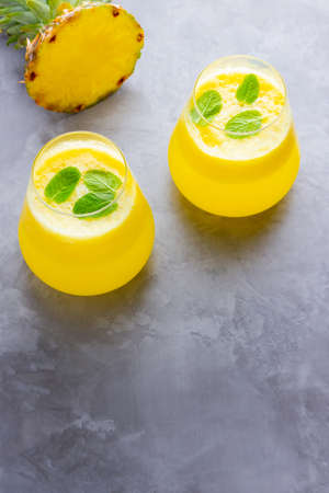 Pineapple cocktail on a gray background. Cold pineapple cocktail with mint. Summer tropical cocktail. Healthy drink. Top view. Copy spaceの写真素材