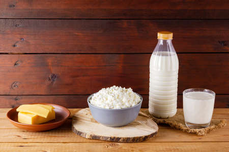 Dairy products on wooden boards. Milk, hard cheese and cottage cheese on burlap. Rustic style. Copy...