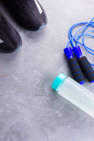 Fitness concept with sneakers, jump rope and bottle of water. Sports equipment on a gray background. Healthy lifestyle concept. Copy space. Top viewの写真素材