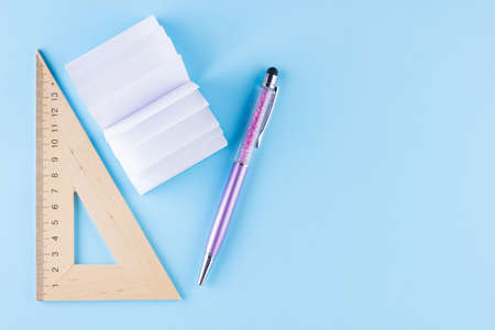 Back to school concept. Stationery on blue background. Pen, triangle and notepad for school. Time to study. Top viewの写真素材