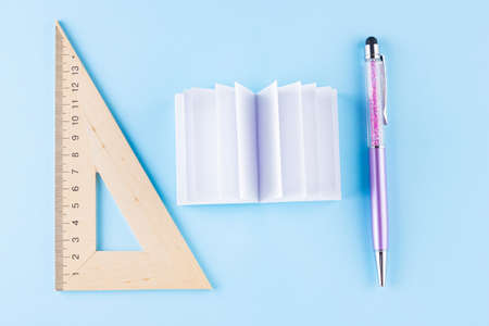 Back to school concept. Stationery on blue background. Pen, triangle and notepad for school. Time to...