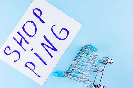 Shopping cart on blue background. Shop trolley at supermarket. Sale and discount. Consumer society trend. Concept of shopping. Copy space. Top viewの写真素材