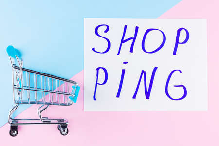 Shopping cart on blue background. Shop trolley at supermarket. Sale and discount. Consumer society trend. Concept of shopping. Top viewの写真素材