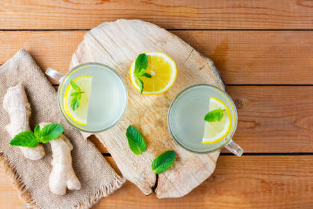 Ginger tea with lemon on a burlap napkin. Two cups of ginger tea with mint on wooden background. Top viewの写真素材