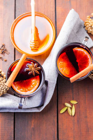 Mulled wine and honey on a wooden background. Two cups of autumn mulled wine and spices. Christmas hot drink in rustic styleの写真素材