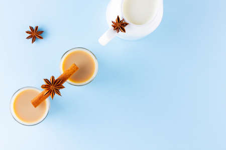 Tea with milk and spices on a blue background. Masala chai in turkish tea cups. Indian national drink and milk jug on a pastel background. Copy space. Top viewの写真素材