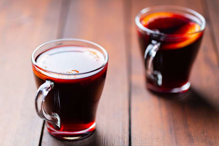 Mulled wine on wooden background. Winter drink traditional for the Christmas holidays. Two glasses of Christmas mulled wine with orangesの写真素材