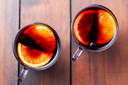 Mulled wine on wooden background. Winter drink traditional for the Christmas holidays. Two glasses of Christmas mulled wine with orangesの写真素材