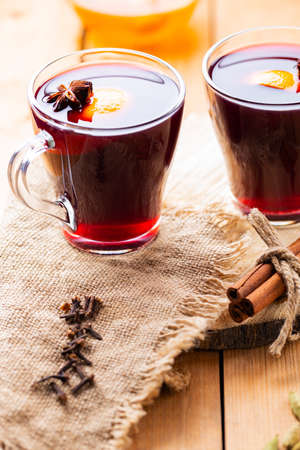 Mulled wine on a wooden background. Autumn mulled wine and spices on burlap. Christmas hot drink in rustic styleの写真素材