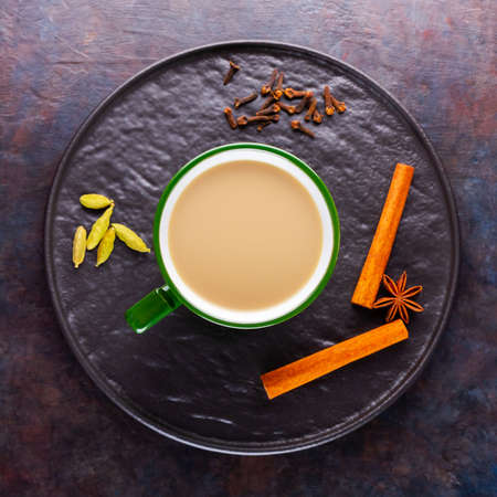 Masala chai tea. Traditional indian drink - masala tea with various spices on a black plate. Ceramic cup of spices tea on a dark background. Minimalismの写真素材