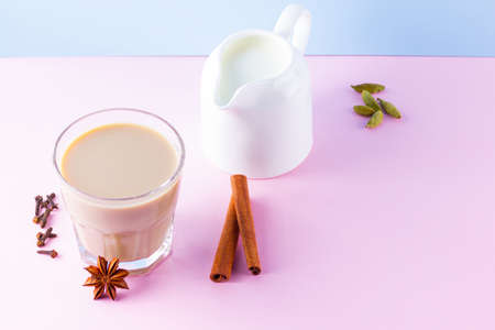 Masala tea and spices on a pink blue background. Masala chai in glass. Indian national drink and milk jug on a pastel background. Copy spaceの写真素材