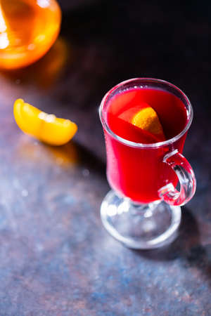Christmas mulled wine on a dark background. Glass of mulled wine glows in the backlight. Traditional hot drink at Christmas timeの写真素材