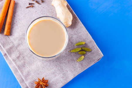 Masala chai tea on a linen napkin. Traditional indian drink - masala tea with various spices. Glass of masala tea on a blue backgroundの写真素材
