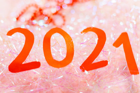 2021 New Year on tinsel. 2021 sign with red paper on blurred background. New Year and Christmas...