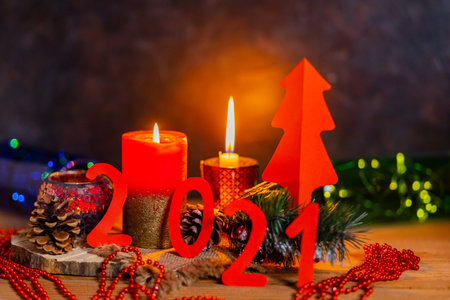 Christmas background with garland lights. New Year concept 2021 on dark background. Inscription 2021 with a candle and fir branches in rustic styleの写真素材