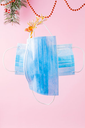 Medical mask and toy deer on a pink background. New Year medical concept with holographic deer and protective face mask. Pandemic Christmas concept. Levitationの写真素材