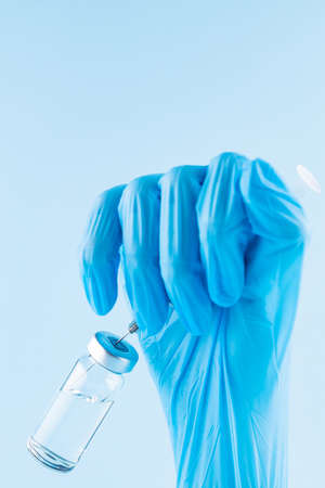 Hand filling syringe with medication. Robotic arm in surgical glove holding syringe with vaccine. Vaccination and immunization concept. Copy spaceの写真素材