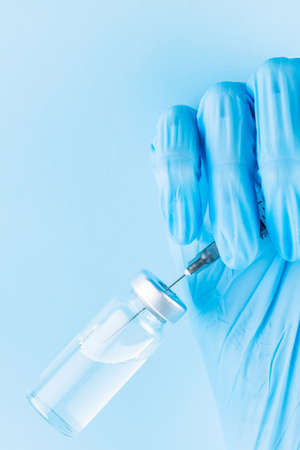 Hand filling syringe with medication. Robotic arm in surgical glove holding syringe with vaccine. Vaccination and immunization concept. Copy spaceの写真素材