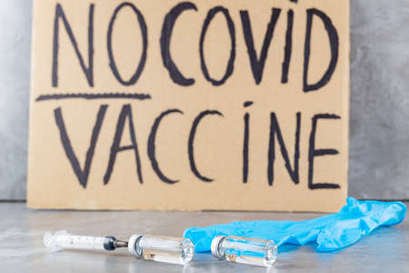 'No covid vaccine' protestive placard. Anti-vaccination poster, vaccine bottle and syringe.