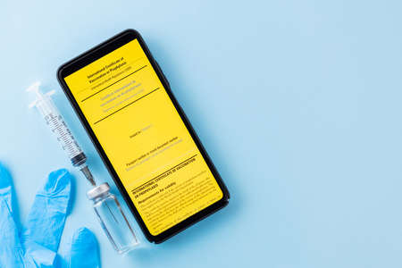 Yellow international certificate of vaccination, vaccine vial and syringe. Vaccine bottle, syringe...
