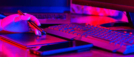 Creative freelancer workplace in neon light. Artificial hand on the keyboard. Place for digital artist to work with laptop, monitor and smartphone. Concept of work at homeの写真素材