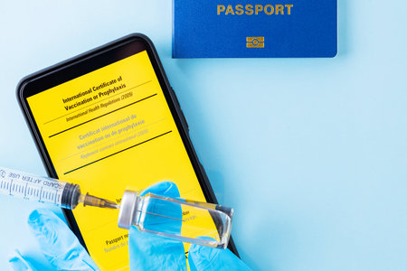 Vaccination concept. Yellow international certificate of vaccination, vaccine vial and syringe. Vaccine bottle, syringe and passport on a blue background. Immunity passportの写真素材