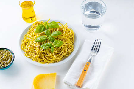Spaghetti with pesto sauce and basil on a white background. Pasta with sauce pesto and ingredients....