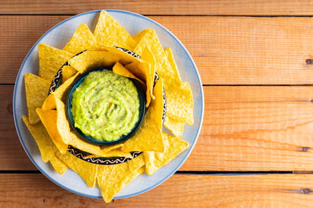 Guacamole with tortilla chips on wooden boards. Nachos chips and Mexican guacamole sauce on a plate. Copy space. Top viewの写真素材
