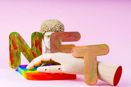 NFT Non-Fungible token. Concept for block chain system. Classical statue and  toy on a pink background. Crypto art concept with an artificial handの写真素材