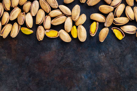 Roasted pistachios nuts on dark background. Pistachio - healthy vegetarian protein nutritious food. Healthy snack. Copy space. Top viewの写真素材