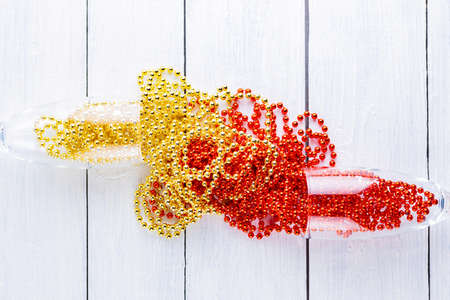 Champagne glasses with Christmas beads on white background. Christmas decorations on wooden boards....