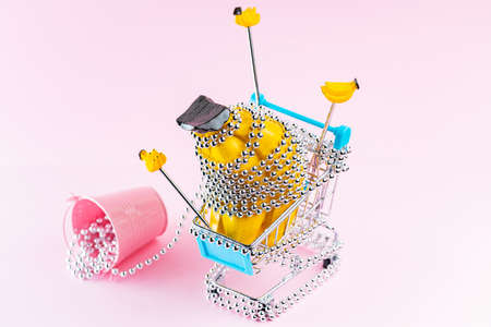 Shopping trolley with silver Christmas beads on a pink background. Shopping cart with creative Christmas gifts. Christmas decoration conceptの写真素材