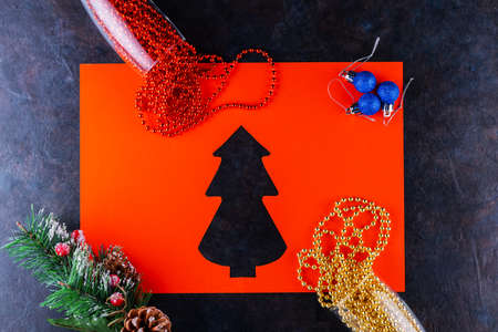 Champagne glasses with Christmas beads on dark background. Christmas balls, multicolored beads and spruce branch. Paper cut christmas tree. Top viewの写真素材
