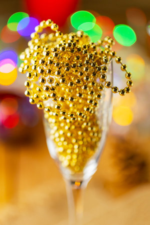 Two champagne glasses with Christmas beads. Christmas decorations in rustic style on bright background with lights. Pine cones and burning candles on the background bokehの写真素材