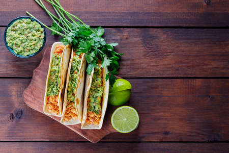 Tacos with fried minced meat and guacamole sauce on a wooden boards. Mexican tacos, cilantro and lime on wooden background. Mexican cuisine. Rustic styleの写真素材