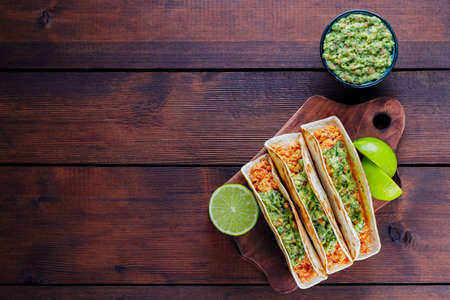 Mexican tacos with fried minced chicken and guacamole sauce on a wooden boards. Tacos, guacamole and lime on wooden background. Mexican cuisineの写真素材